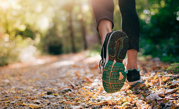 Closeup of running shoe of the person running in the nature with beautiful sunlight.