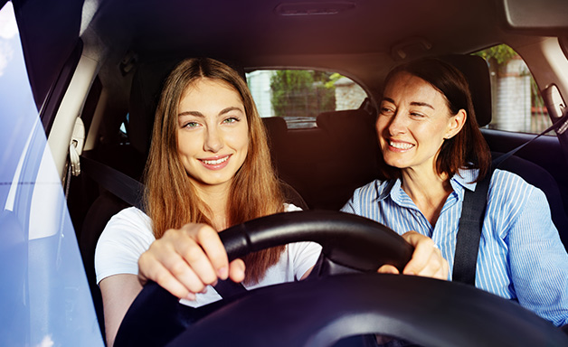 Happy adult daughter driving her mother in car