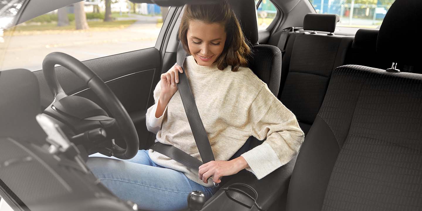 Young adult putting seat belt on