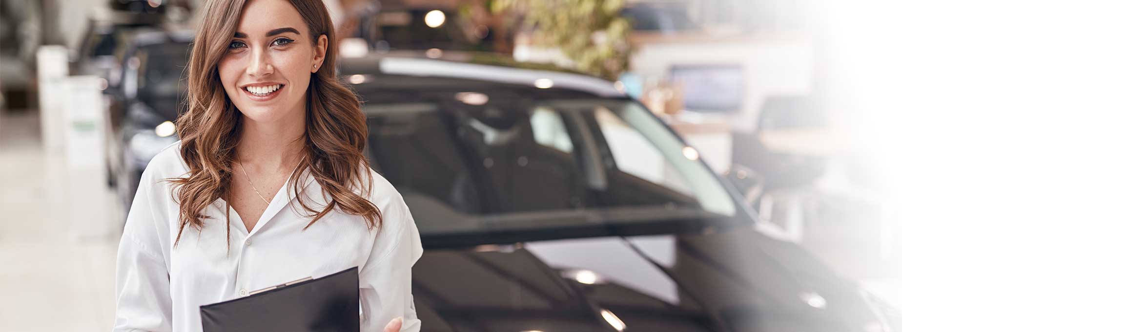  A young woman with a clipboard standing in front of a car